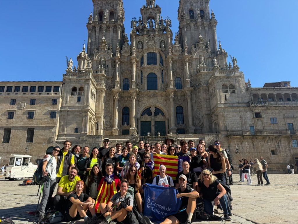 Grup de joves excursionistes amb motxilles caminant per un sender rural envoltat d'arbres